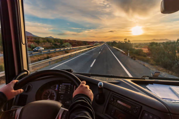 view from the driver's seat of a truck of the highway and a landscape of fields at dawn, with a dramatic sky. - highway truck road driving imagens e fotografias de stock