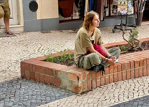LAGOS,  Portugal - October 20,  2022. Young woman listening to the performance of street musicians in the city of Lagos.