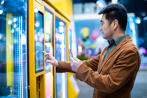Asian middle-aged man shopping in vending machine