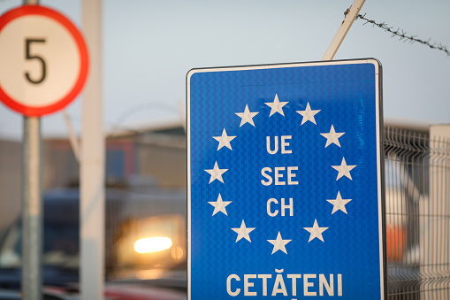 Details with an European Union flag and barbed wire at a Romanian border crossing.