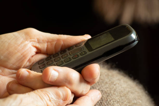 istock old woman's hands hold push-button telephone at home 1435513849