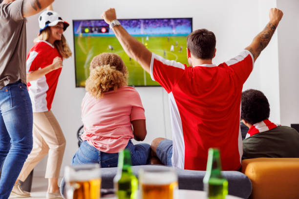 istock Friends cheering while watching football on TV 1435515142