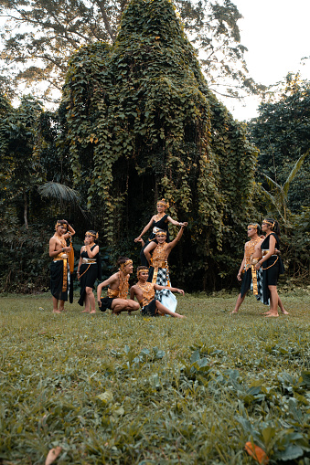 Indonesian dancers pose with their bodies while wearing a traditional golden costume from Javanese in front of the forest
