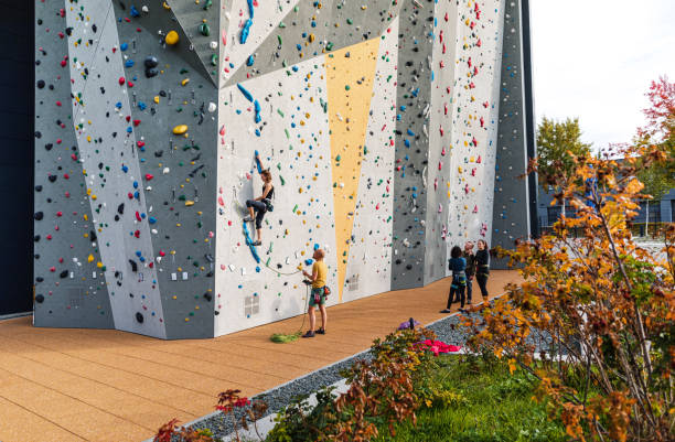 Woman doing rock climbing on artificial climbing wall with instructor standing below