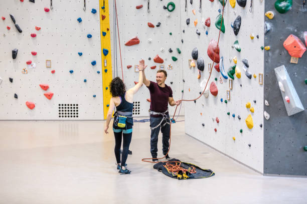 Male and female climber giving each other high five after training session on artificial rock climbing wall. Man and woman looking happy at a rock climbing gym.