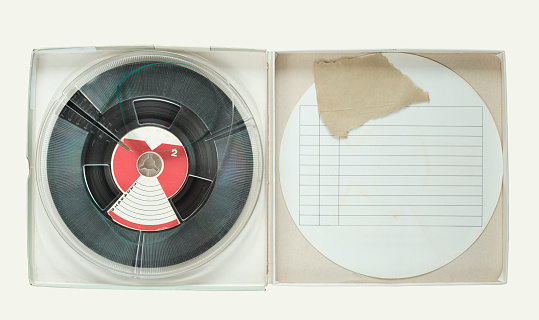 Vintage magnetic audio reel in cardboard box and blank paper inlay, isolated on white, free copy space