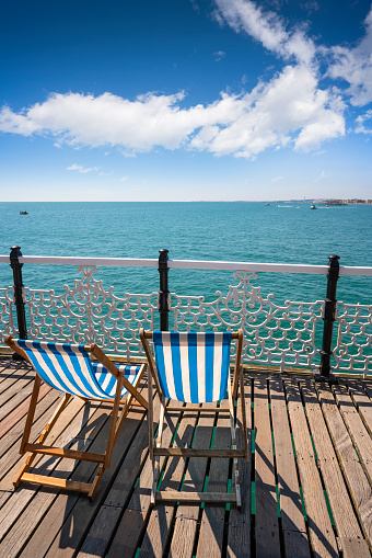 Brighton seaside resort beach and Brighton Palace Pier beach lich chair in a summer sunny blue sky day, Great Britain, England.