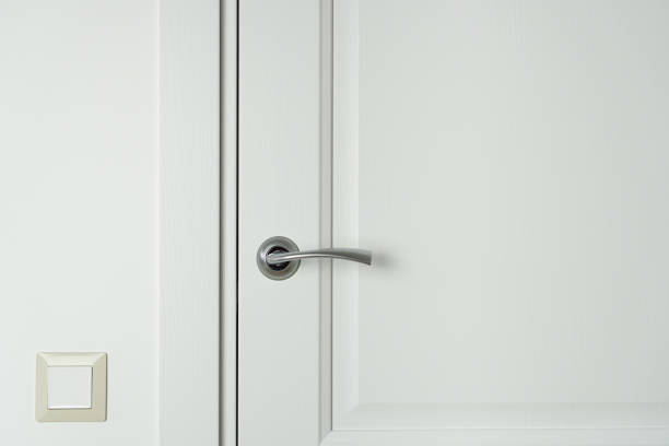 istock Closed white wooden interior door with handle and light switch on the wall. 1435520466