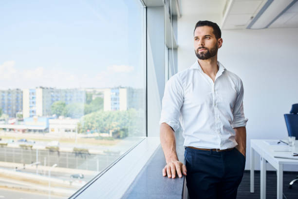 istock Thoughtful handsome businessman at work standing at office looking out window. 1435520942