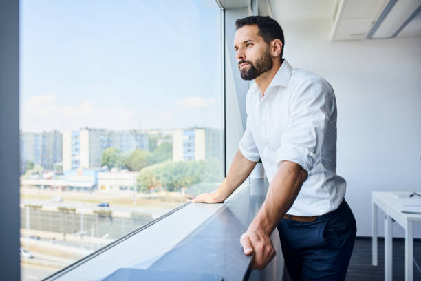 Thoughtful handsome businessman looking through window at office