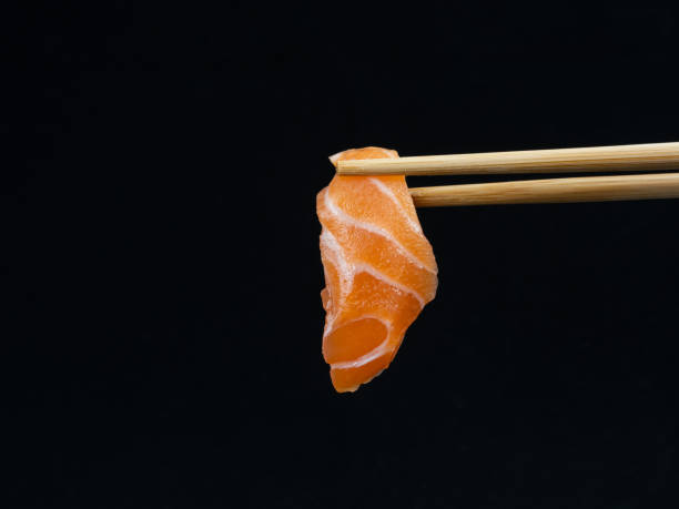 istock Chopsticks hold salmon sashimi on black background 1435521055
