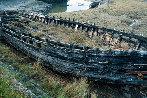 A large wooden wreck lie by the beach in Devon, UK
