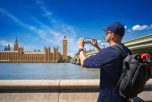 London tourist middle age man shooting smartphone photos at Big Ben Westminster bridge over Thames river England UK Great Britain United Kingdom