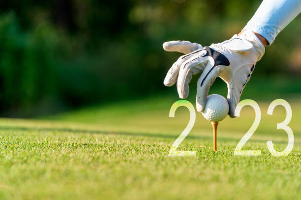 mano ravvicinata donna golfista che mette la pallina da golf per il felice anno nuovo 2023 sul golf verde per nuovi sani.  spazio di copia. concetto di salute e vacanza - golf foto e immagini stock