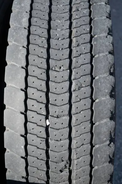 Photo of Vertical of a detail of the texture and drawing of the double wheel of a truck.