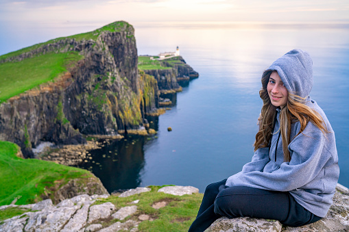 Blond girl with hood in Skye island Nest Point lighthouse in Highlands Scotland UK in United Kingdom