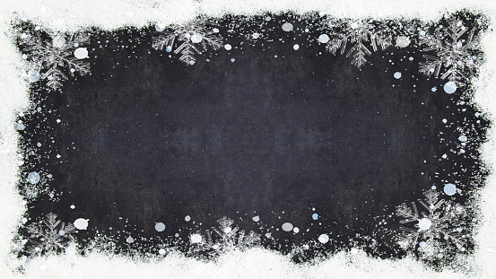 winter / Advent / christmas Background template - Frame made of snow with snowflakes and ice crystals on black concrete chalkboard texture, top view with space for text