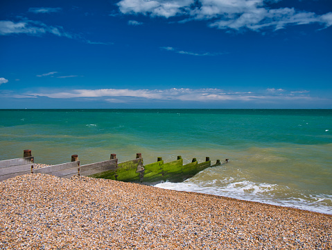 A wooden breakwater on the shingle beach in Kingsdown in Kent. Taken on a clear, sunny day with a blue sky, light cloud and a turquoise sea.