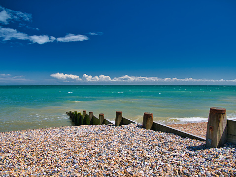 A wooden breakwater on the shingle beach in Kingsdown in Kent. Taken on a clear, sunny day with a blue sky, light cloud and a turquoise sea.