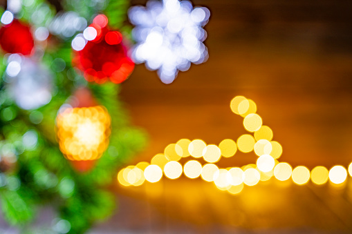 Blurred Christmas fir tree background with baubles, snowflake and glowing Christmas lights bokeh