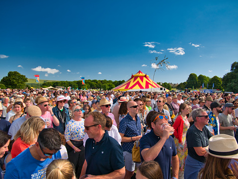 A large crowd at an outdoor summer music festival in England, UK. Taken on a sunny day with a blue sky.