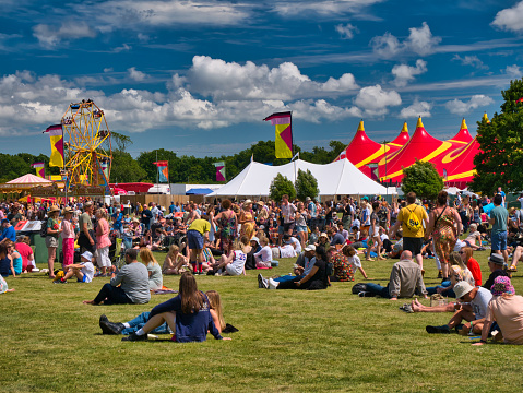 A large crowd at an outdoor summer music festival in England, UK. Taken on a sunny day with a blue sky.