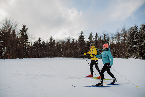 Senior couple skiing together in the middle of snowy forest