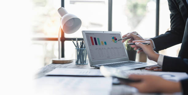 istock Teamwork with two business people analysis cost graph on laptop at meeting room. 1435547979