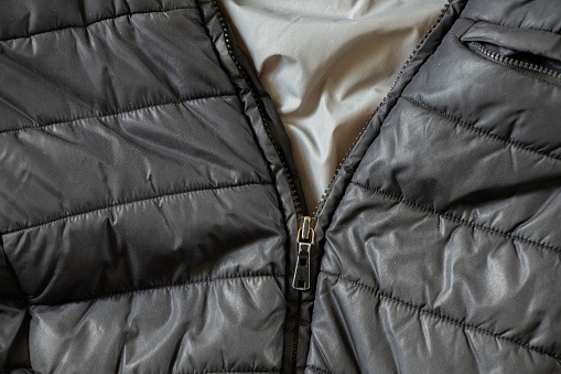 women's insulated black down jacket as a background with an open zipper, a background of soft black fabric