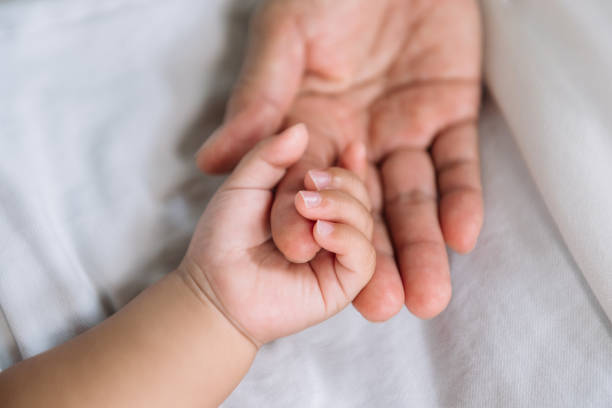 istock Close up baby hand on mother's hand 1435558381