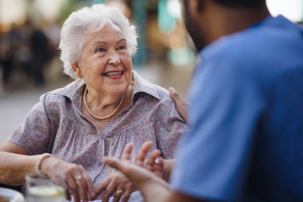 cuidador hablando con su cliente en la cafetería, pasando un buen rato juntos. - residencia de ancianos fotografías e imágenes de stock