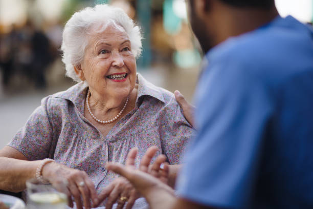 caregiver che parla con il suo cliente al bar, divertendosi insieme. - senior adult nursing home assisted living talking foto e immagini stock