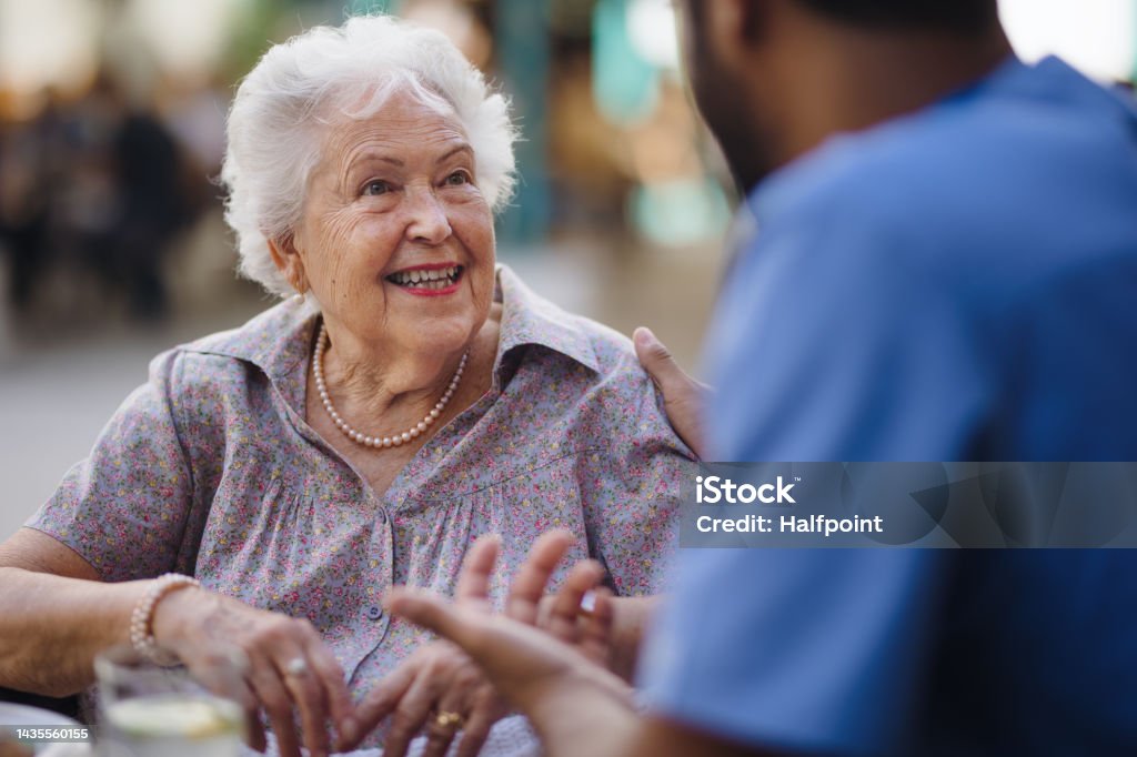 Caregiver talking with his client at cafe, having nice time together. Caregiver talking with his client at a cafe, having nice time together. Senior Adult Stock Photo