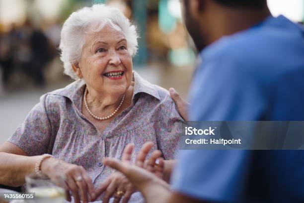 Caregiver Talking With His Client At Cafe Having Nice Time Together Stock Photo - Download Image Now