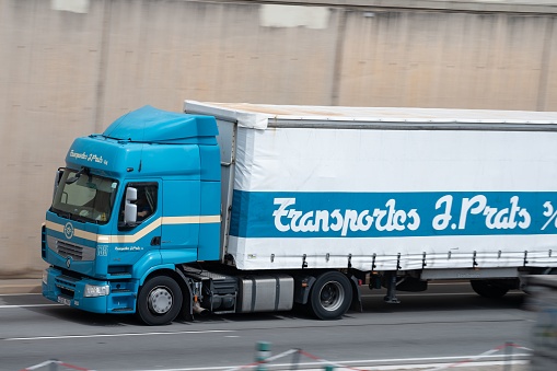 Barcelona, Spain – August 20, 2022: Blue Renault Premium loaded truck a white container trailer along Barcelona's Ronda Litoral