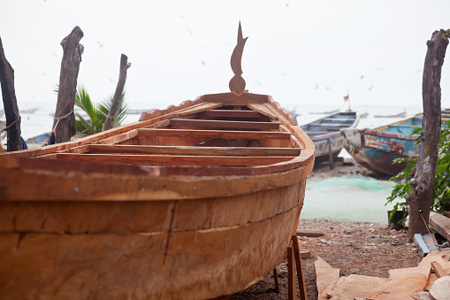 A new fishing boat, a pirogue, under construction using local timber at a boatyard on the Atlantic coast of Gambia in tropical West Africa. Good copy space.