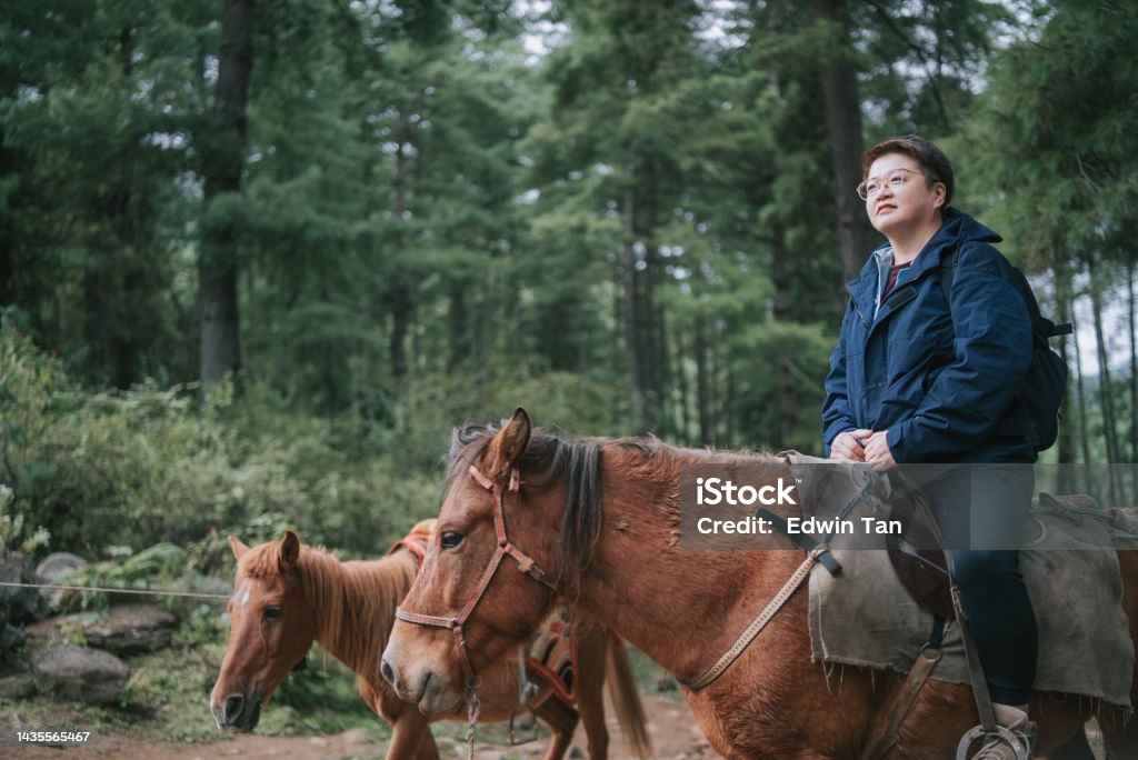 Asian Chinese female Tourist Riding horse prepare hiking up to Taktsang Monastery , Tiger Nest in Bhutan Bhutan Stock Photo