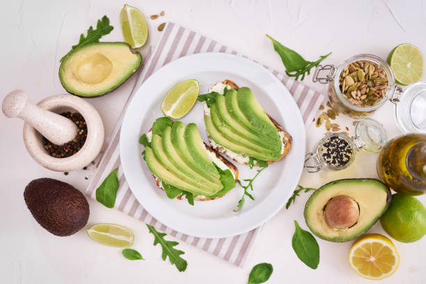 istock Freshly made Avocado and cream cheese toasts on a white ceramic plate and ingredients 1435566931