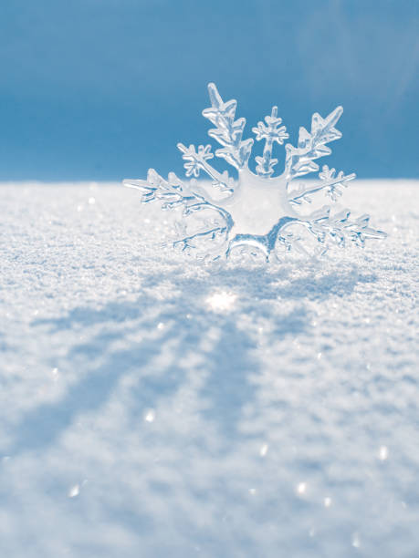 hermoso cristal de hielo se encuentra en la nieve y brilla al sol, bokeh en el fondo azul - ice crystal winter nature ice fotografías e imágenes de stock