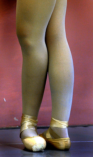 Ballet student positions her feet during ballet practice.