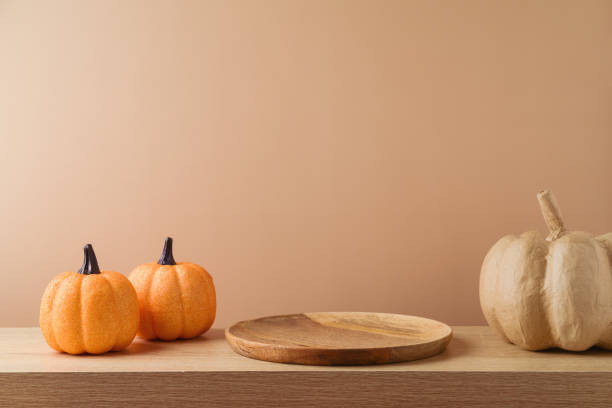 istock Empty wooden plate on table with pumpkin over modern background. Halloween or Thanksgiving mock up for design and product display 1435584291