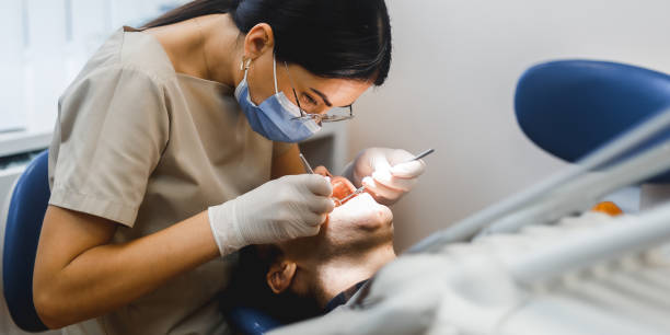 두 사람의 그룹 초상화, 남자를위한 현대 클리닉에서 치료를하는 여성 치과 의사. 치과를위한 실내 의료 개념 사진. 치과 사무실, 환자와 함께 클리닉에서 일하는 의사. - female dentist 뉴스 사진 이미지