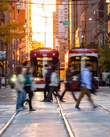 Toronto, Canada - October 21, 2022 : Pedestrians crossing the street during rush hour sunset with 504 King Street streetcars
