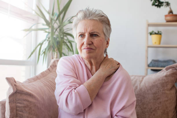 nieszczęśliwa 60-letnia kobieta ma ból szyi w domu - 60 65 years zdjęcia i obrazy z banku zdjęć