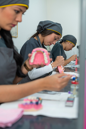 Latina dental students all between the ages of 20 and 24 perform their exercises in class while working on ceramic teeth