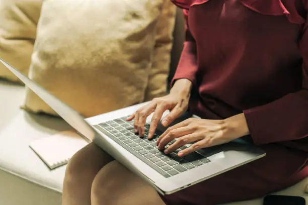 Photo of Asian Virtual assistant woman using laptop computer typing report to client.