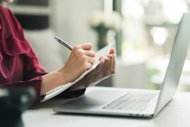 Web designer Woman holding pen and writing on a book at cafe