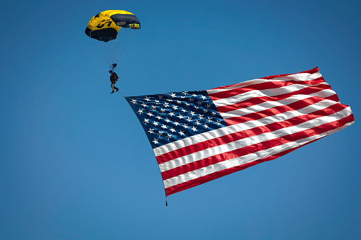 Miramar, California, USA - September 23, 2022: A member of the US Navy Leap Frogs parachute team brings the American flag to the 2022 Miramar Airshow.