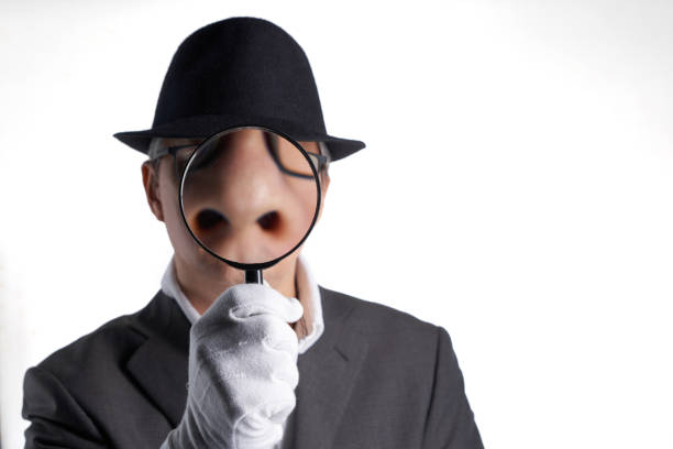 istock businessman with hat holding magnifying glass against white background 1435602917