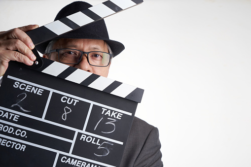 Young man holding a clapperboard over isolated white background. Studio Shot, Horizontal Composition, Image taken with Sony A7RII camera system and developed from camera RAW.